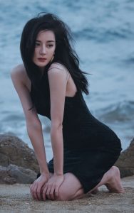 迪丽热巴光着美足踩在海滩上，身着黑裙展露迷人风姿（第1张/共14张）