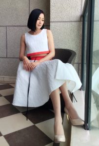 演员万绮身穿优雅白裙搭配超波丝袜坐在落地窗前拍照片
