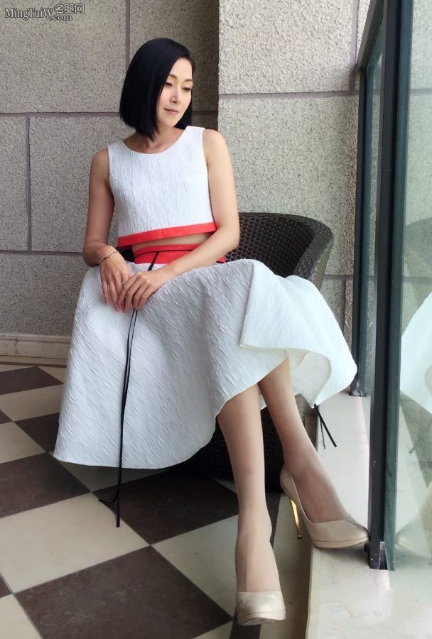 演员万绮身穿优雅白裙搭配超波丝袜坐在落地窗前拍照片（第1张/共3张）